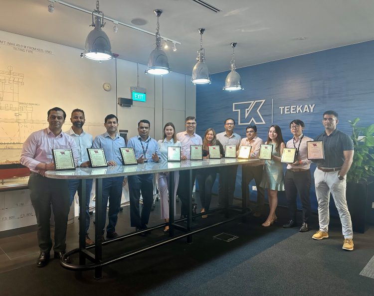 A mix of shore staff smiling and holding plaques behind a long table