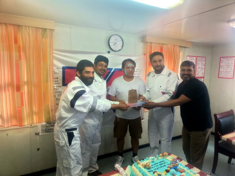 5 seafarers onboard surrounding the retiree, Juliano standing in the middle of everyone