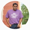 a young man in a purple shirt with hand in his pocket