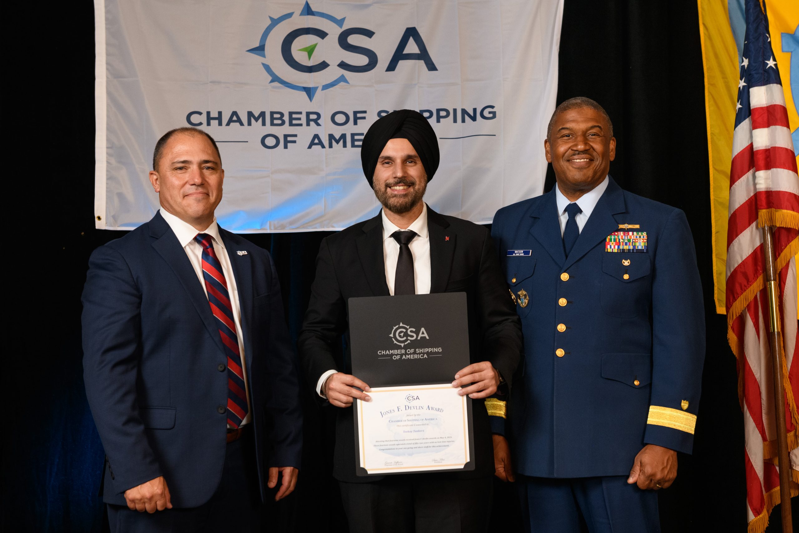 Manmeet stands in the middle holding a certificate with 2 smiling men on both his side